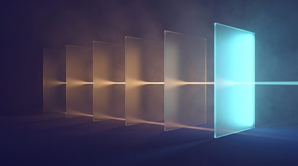 Five frosted glass panels standing in a row on a dark indigo floor, the first four lit dim amber and the last lit cyan, a thin beam of light passing through them