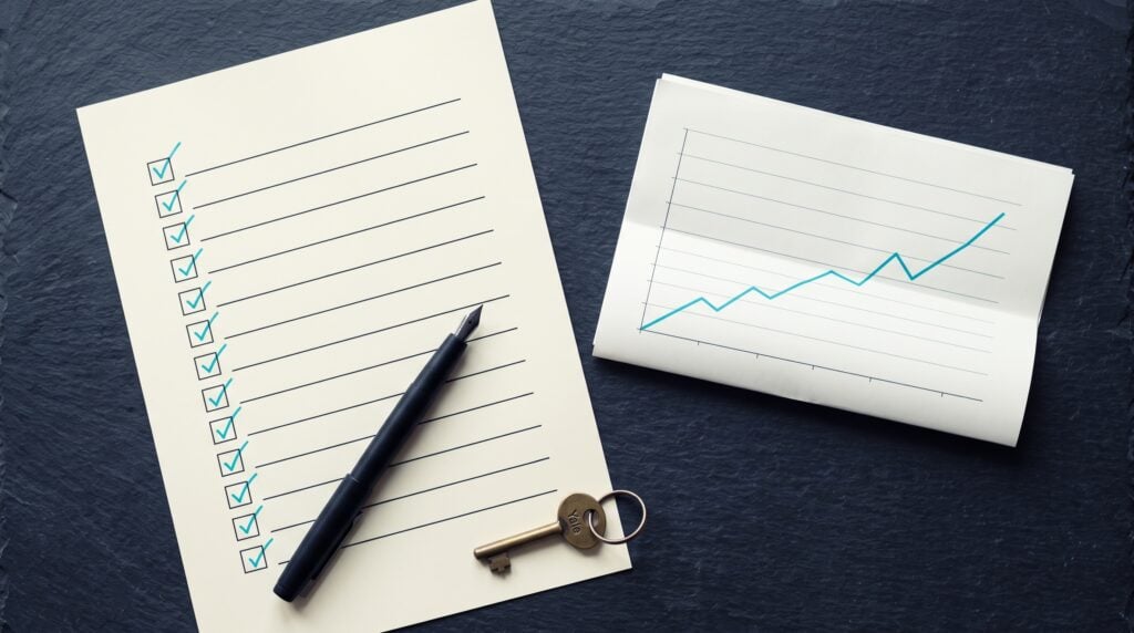 Printed agency due diligence checklist with ticked boxes and a performance report on a dark desk
